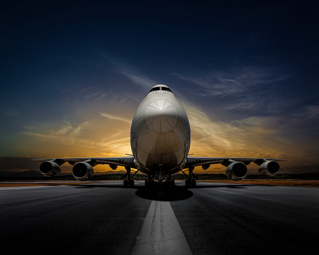 Passenger plane on runway at sunset