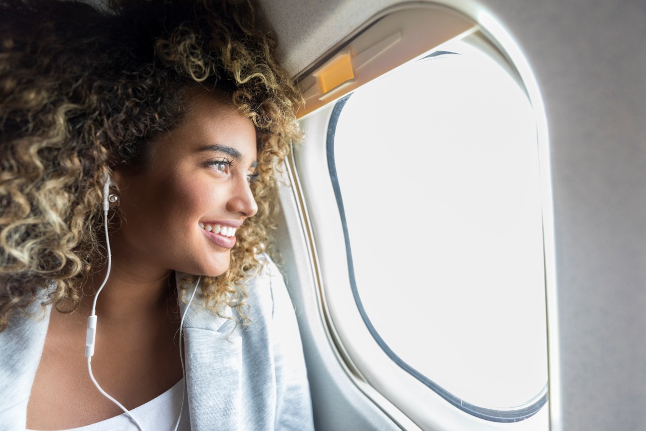 young-woman-looking-through-window-airplane-getty-1022880168.jpg