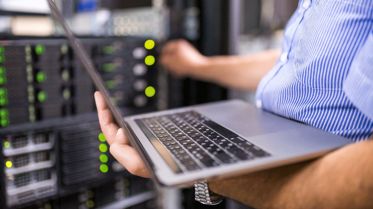 IT engineer holding laptop near servers close up
