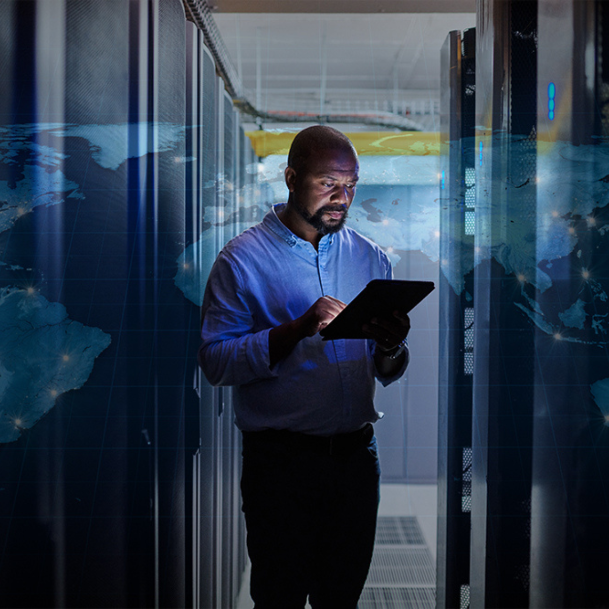 Man holding a tablet in a data center with a globe overlay in the background